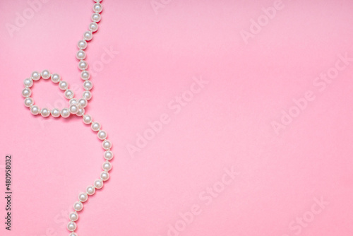 Fotografie, Obraz A pearl necklace lies on a pink background