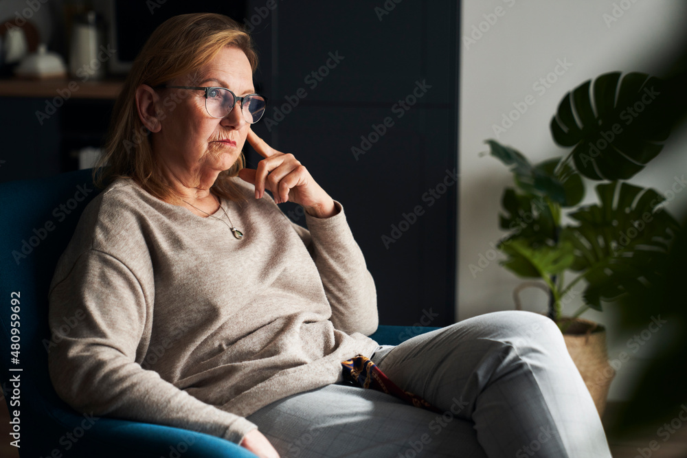 Fototapeta premium Thoughtful and silent caucasian senior woman sitting on the chair