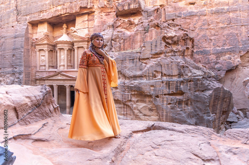 woman dressed in traditional clothes and headscarf staying at the top of rock on the background is Petra palace Jordan © юля ком
