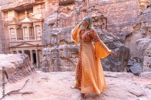woman dressed in traditional clothes and headscarf staying at the top of rock on the background is Petra palace Jordan © юля ком