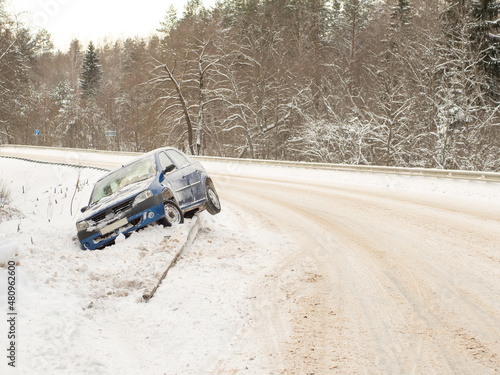 Abandoned car on the side of the road after a traffic accident. Symbolizes hazardous conditions in winter with ice, snow and jerk.
