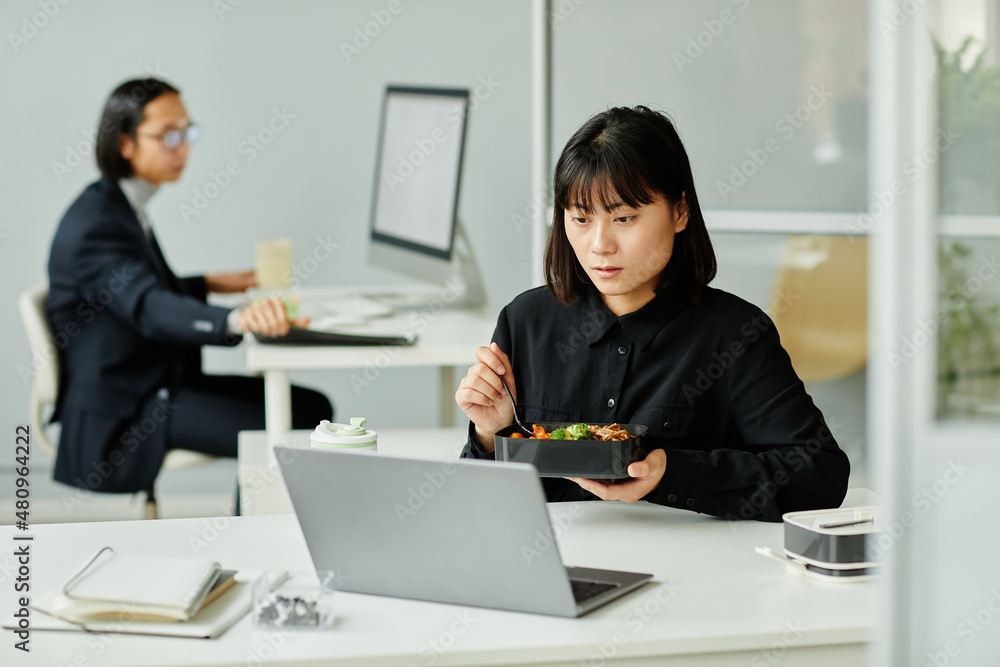 Portrait of young Asian woman enjoying hot lunch at desk in office, copy space Portrait of young Asian woman enjoying hot lunch at desk in office, copy space