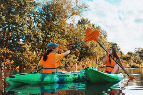 Two young happy women are kayaking and high-fiving on the oars. Outdoor activity