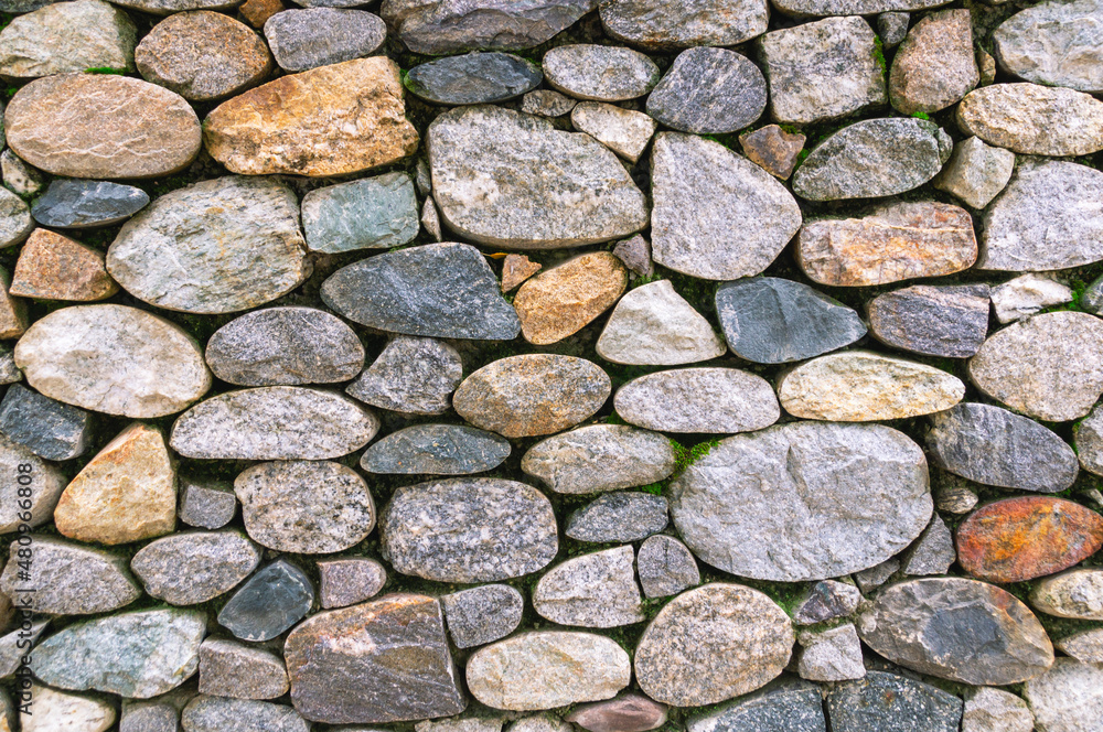 Background of stones. A wall of multicolored stones. The masonry is made of untreated stones. A wall of large stones. Background of stones. A wall of multicolored stones. The masonry is made of untreated stones. A wall of large stones.