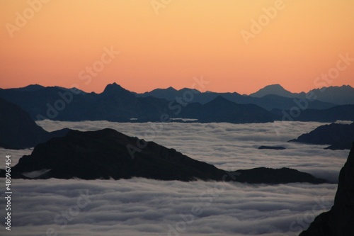 Mar de nubes en la montaña con cielo anaranjado al anochecer desde refugio de Collado Jermoso en Picos de Europa Leon España