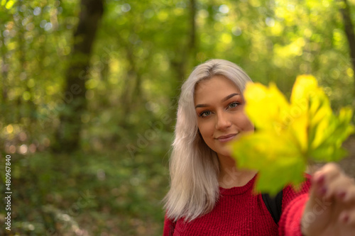 Beautiful blonde woman holding a dry leaf while out in the nature