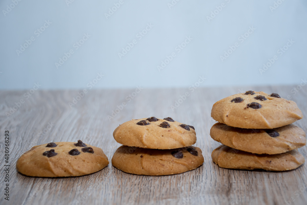 Picture shows chocolate chip cookies stacked on a wooden board. Picture shows chocolate chip cookies stacked on a wooden board.