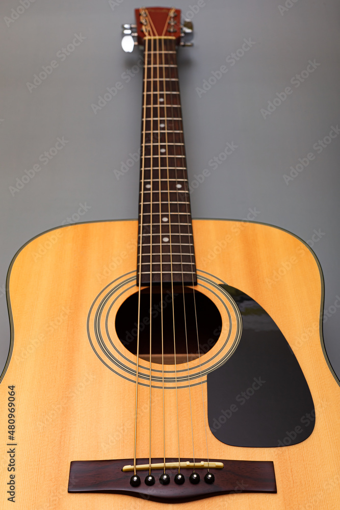  upper soundboard of an acoustic yellow guitar close-up on a gray background