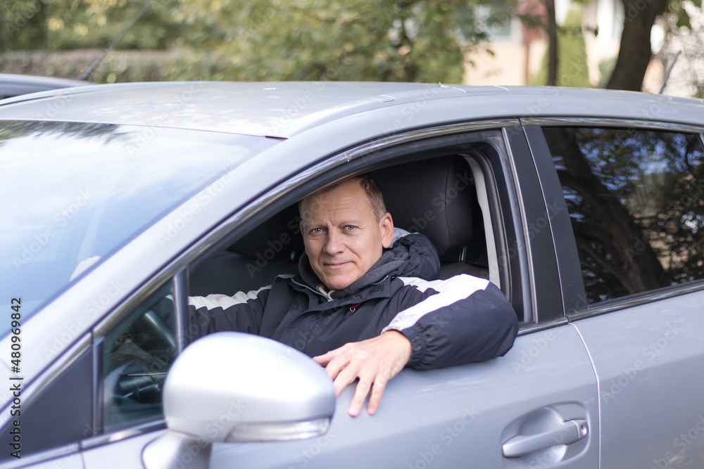 middle-aged man, 55-60 years old, driver, sits in a car and smiles middle-aged man, 55-60 years old, driver, sits in a car and smiles