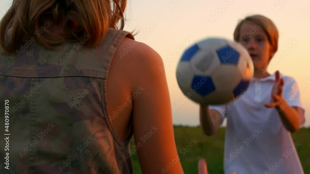 Brother and sister playing ball in the backyard in the rays of the setting sun. Happy teenagers play together and smile at each other. Teenage children have a carefree childhood. Brother and sister playing ball in the backyard in the rays of the setting sun. Happy teenagers play together and smile at each other. Teenage children have a carefree childhood.
