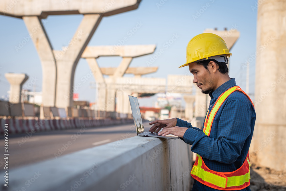 Obraz premium Male engineer working on a laptop computer at a highway construction site