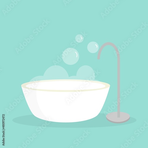 Freestanding bathtub with bubbles on blue bathroom wall background. Hygiene interior design body skin care concept
