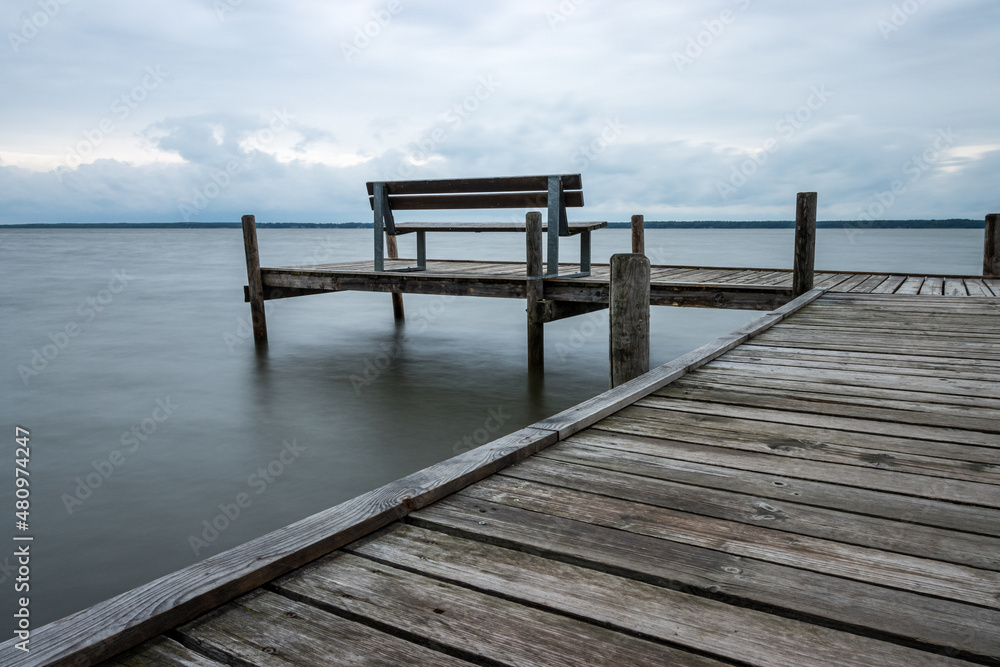 Naklejka premium Wooden jetty with benches by the sea