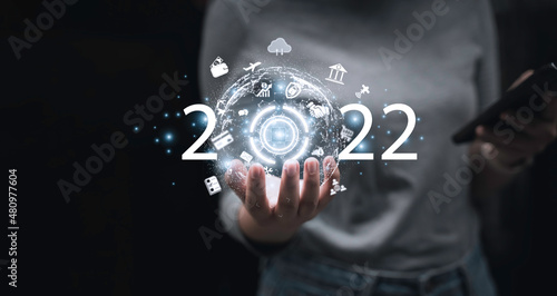 2022 new smart future technology ,Business development and growth concept.businessperson holding digital earth and word 2022 on dark blue background.Development to success and motivation,