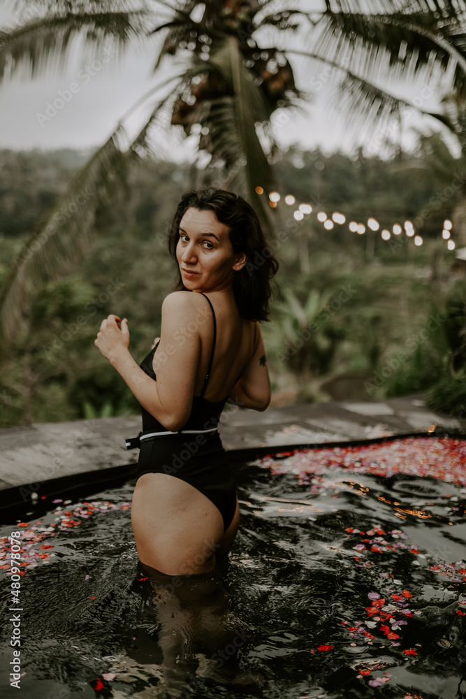Young traveller relaxing by the pool in a hotel in Bali, surrounded by jungle, palm trees and green landscapes. Young traveller relaxing by the pool in a hotel in Bali, surrounded by jungle, palm trees and green landscapes.