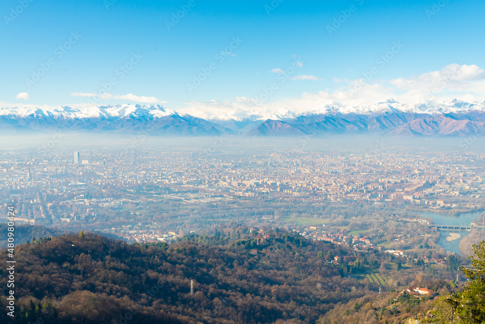 Aerial view of the city of Turin, Piedmont, Italy, under a blue sky.  On the background italian alps with peaks full of snow and ice.