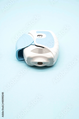 Asthma inhaler on blue background, copy space. Aerosol for inhalation, treatment of bronchial asthma, COPD. Pharmaceutical product for treat lung inflammation and prevent asthma attack. 