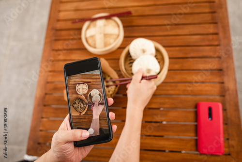 Mano de un hombre con un teléfono celular tomando una fotografía a la comida en su mesa.	
 photo