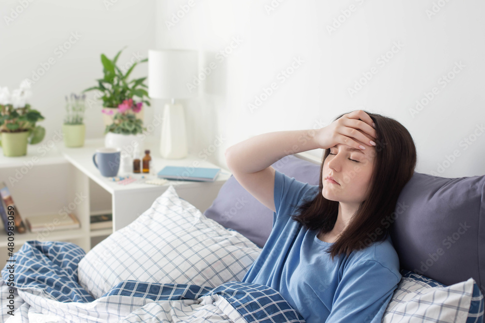 teen girl with headache on bed in white room teen girl with headache on bed in white room