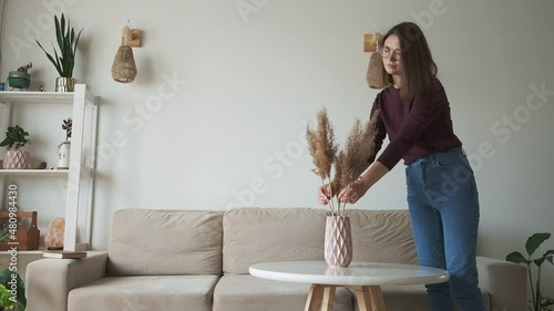 Young woman decorates home interior and sits on the sofa to relax and read book