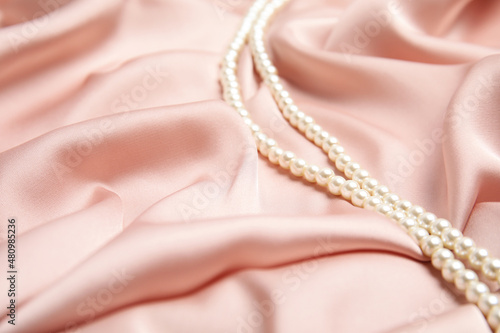 Beautiful pearls on pink silk, space for text