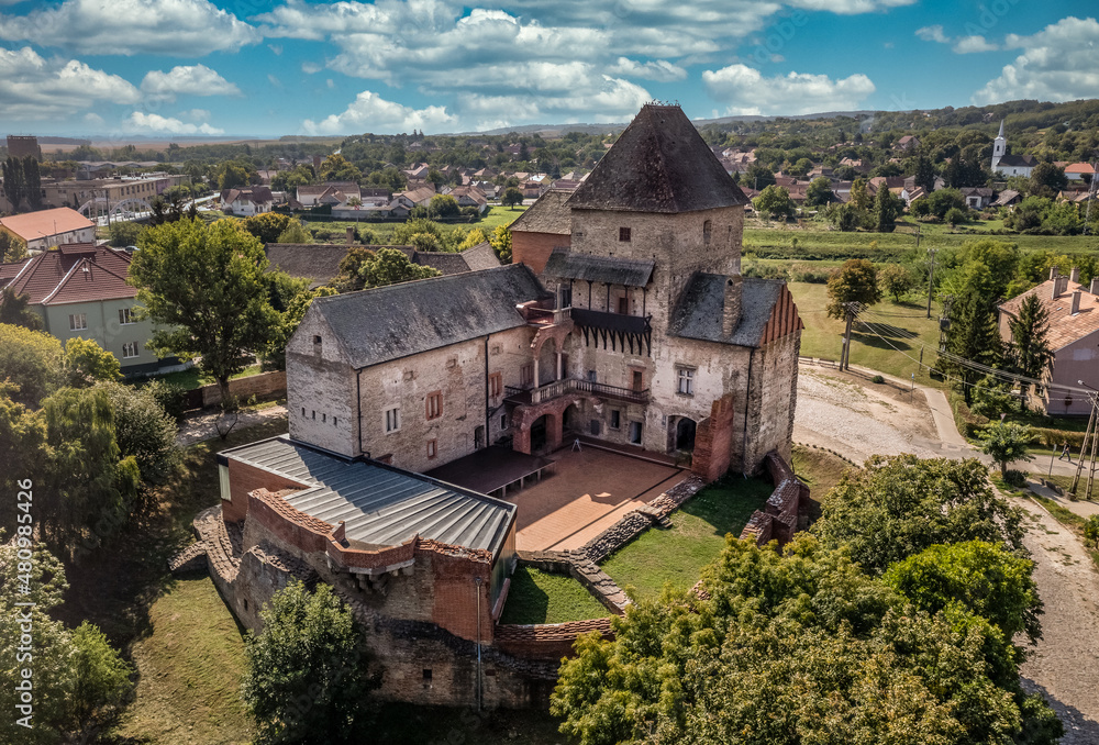 Aerial view of medieval Gothic Simontornya castle protecting the cross on the Sio river  in Tolna county Hungary with restored donjon, palace, brick walls blue cloudy sky
