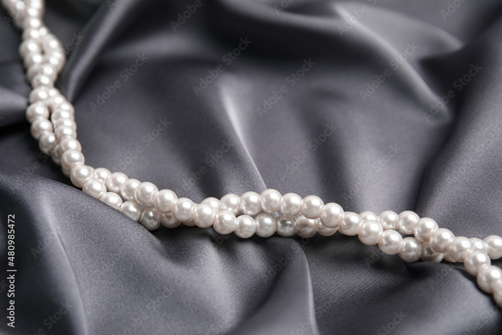 Beautiful white pearls on delicate grey silk, closeup