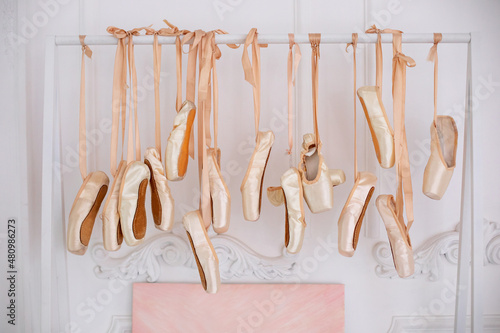 Fotografia Many hanging ballet shoes on white wall background in studio