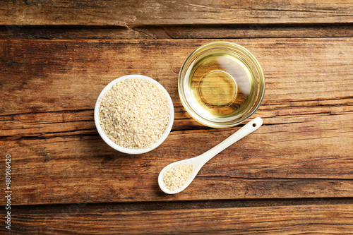 Fotografija Fresh sesame oil and seeds on wooden table, flat lay