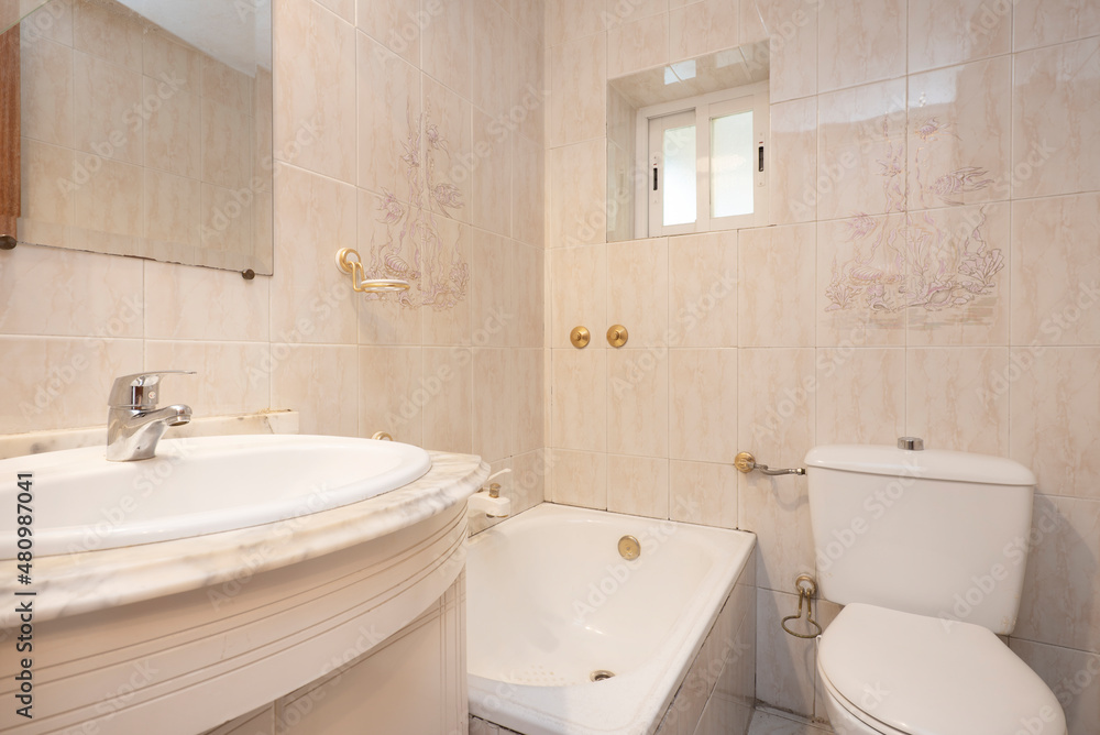 Fototapeta premium Bathroom tiled with cream tiles with white marble top and bathtub