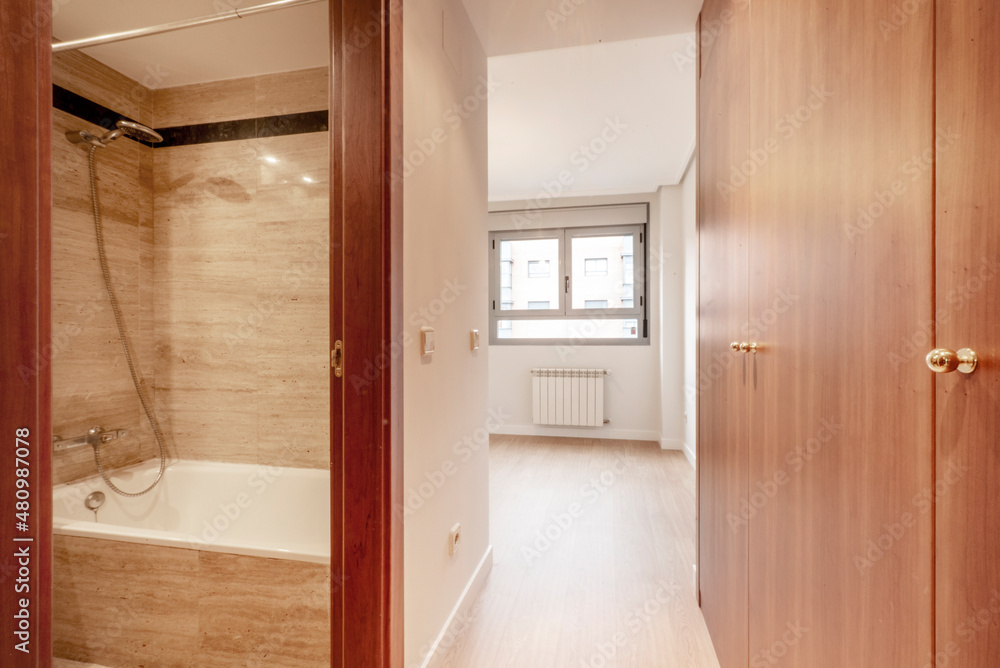 Room with marble tiled toilet with white bathtub and walk-in closet at the exit Room with marble tiled toilet with white bathtub and walk-in closet at the exit