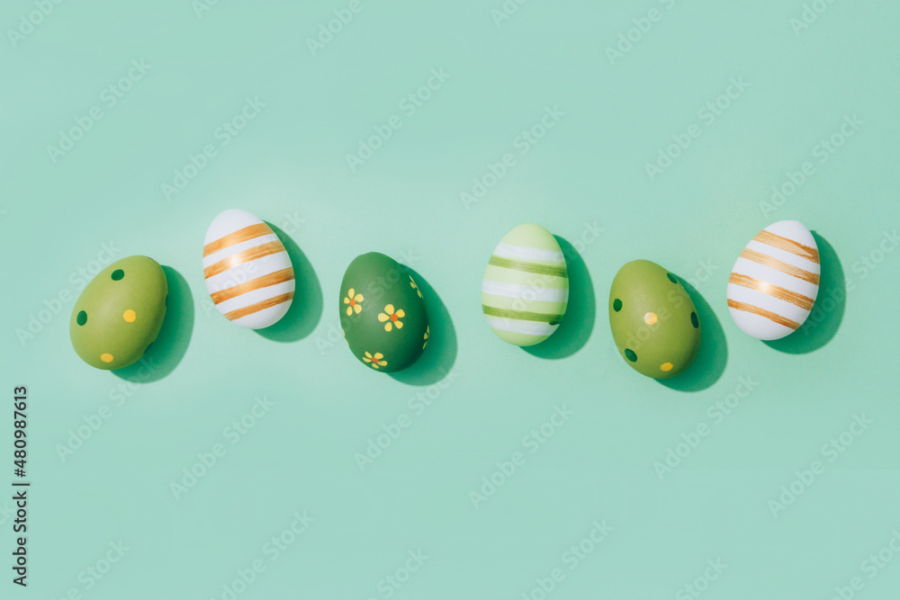 Fototapeta premium Easter greeting card - Easter eggs on pastel mint background with copy space. Flat lay, selective focus. Central composition