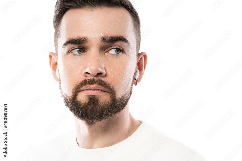 Handsome bearded man in white clothes using wireless earbuds on white background Handsome bearded man in white clothes using wireless earbuds on white background