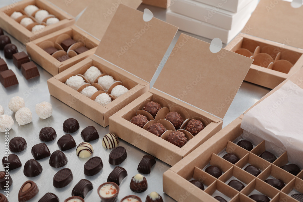 Different delicious chocolate candies and boxes on white table. Production line