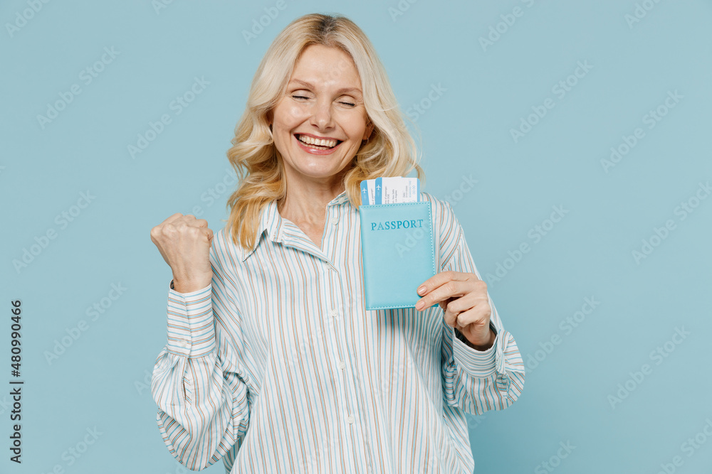 Traveler elderly tourist woman wear shirt hold passport tickets do winner gesture isolated on pastel plain light blue background Passenger travel abroad on weekends getaway Air flight journey concept Traveler elderly tourist woman wear shirt hold passport tickets do winner gesture isolated on pastel plain light blue background Passenger travel abroad on weekends getaway Air flight journey concept