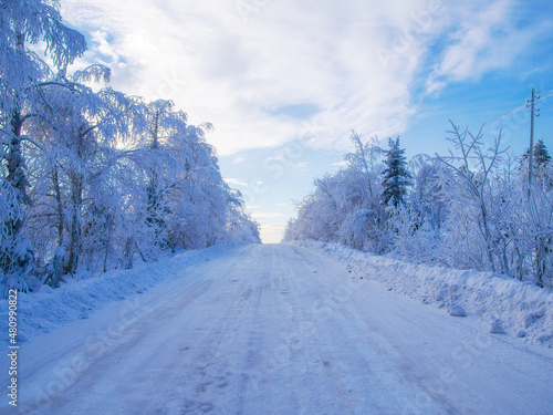 Snow-covered road among snow-covered trees in the winter Ural forest.