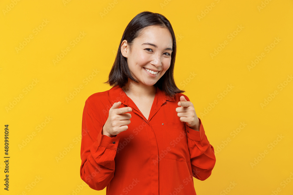 Charismatic stunning vivid young woman of Asian ethnicity 20s years old wear orange shirt pointing index fingers camera on you motivating encourage isolated on plain yellow background studio portrait Charismatic stunning vivid young woman of Asian ethnicity 20s years old wear orange shirt pointing index fingers camera on you motivating encourage isolated on plain yellow background studio portrait