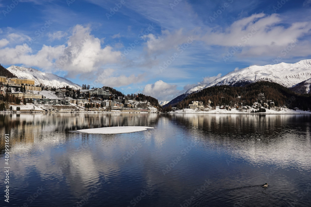Dramatic reflection of the Saint Moritz famous village in the lake on a sunny winter day in Canton Graubunden in the alps in Switzerland