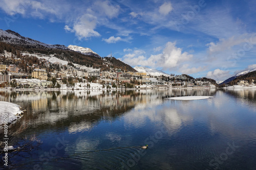 Dramatic reflection of the Saint Moritz famous village in the lake on a sunny winter day in Canton Graubunden in the alps in Switzerland