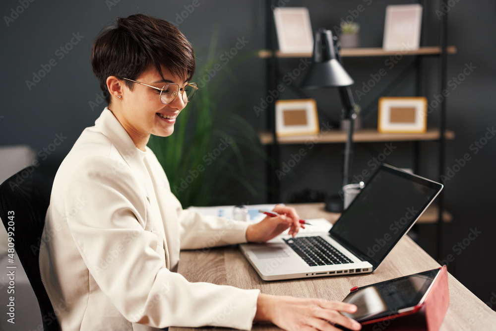 Young business woman working at home with laptop and papers on desk. Young business woman working at home with laptop and papers on desk.