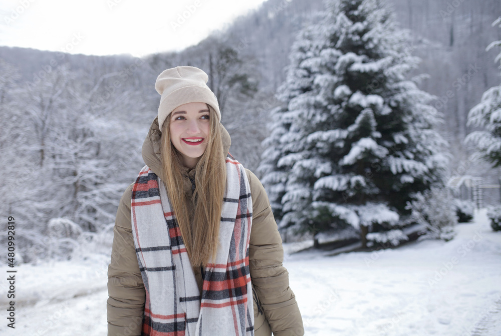girl in winter in a hat against the backdrop of snow-capped mountains and forests. happy looking into the distance girl in winter in a hat against the backdrop of snow-capped mountains and forests. happy looking into the distance