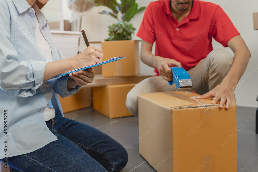 Asian couple checking the list of stuff before packing to cardboard for relocation move out of apartment. Asian couple checking the list of stuff before packing to cardboard for relocation move out of apartment.