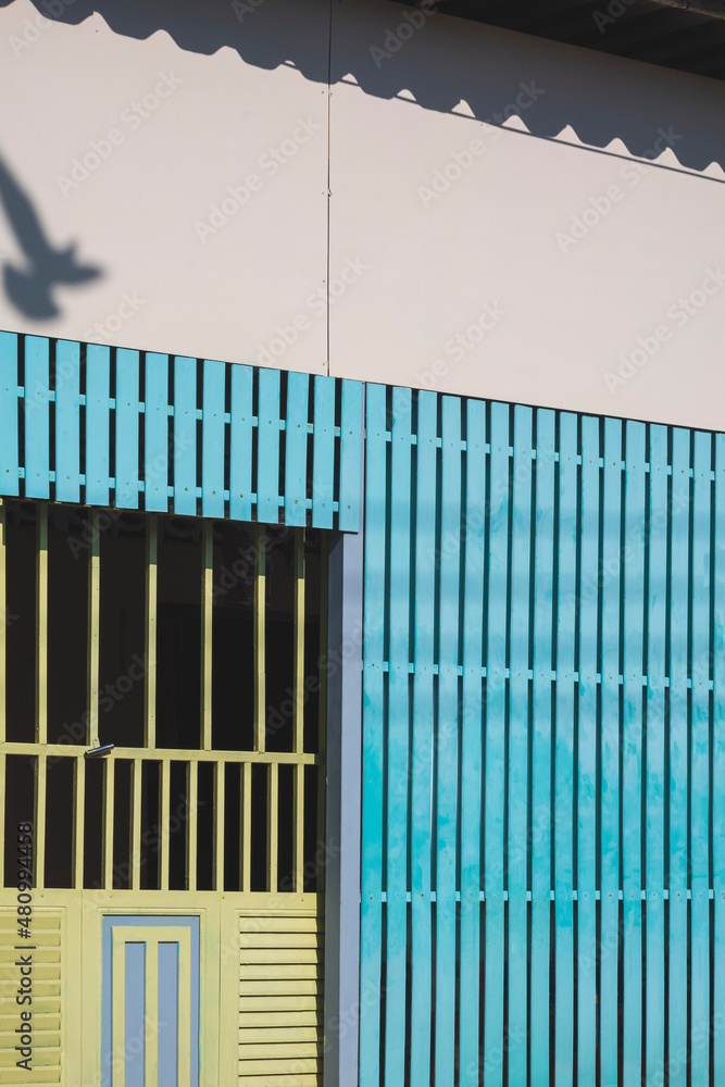 Side view of green steel entrance door on blue wooden lath and gypsum wall of vintage house in vintage style Side view of green steel entrance door on blue wooden lath and gypsum wall of vintage house in vintage style