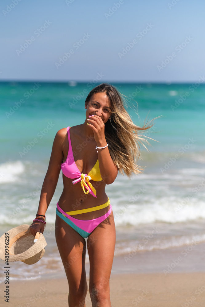 Woman in bikini on the beach walking and smiling