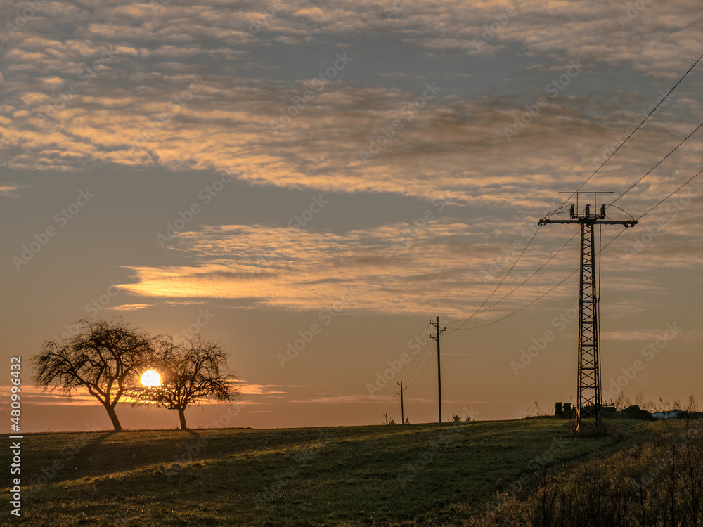 Obraz premium Strommast und Feldweg bei Sonnenuntergang