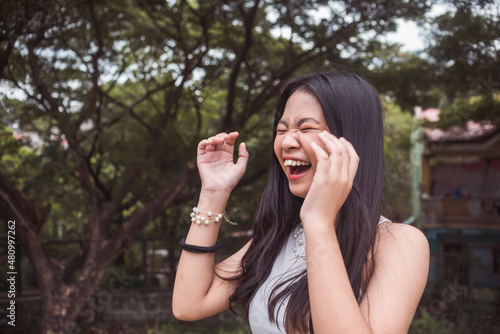A hysterical young woman laughs uncontrollably. Reacting to a very funny joke. Copyspace on the left. Outdoor scene. photo