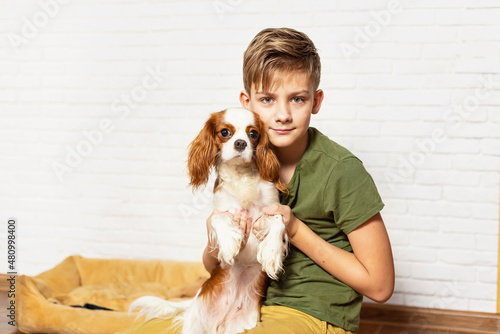 Kid with dog indoor. Teen boy is training her puppy at home. Happy boy playing hugging his funny pet puppy dog domestic animals. Best friend and pet. Lovely dog