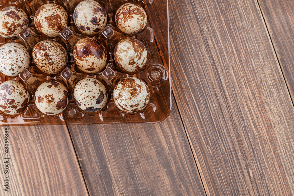 Group of quail eggs are put on clear tray on wooden table.