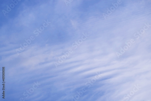 Beautiful white altostratus clouds spreading across the bright blue sky © jobi_pro