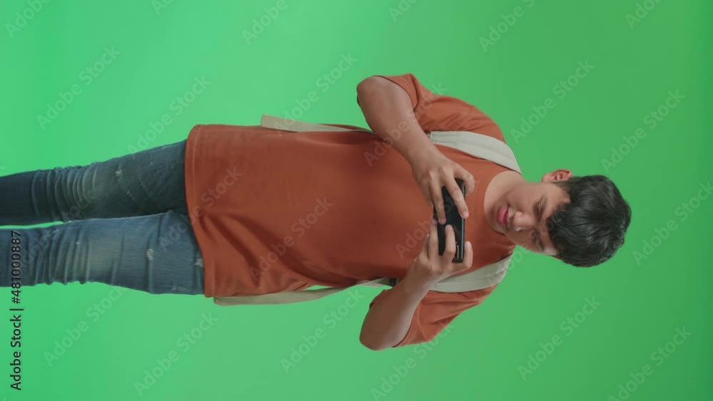 The Front View Of Asian Boy Student Wearing A Backpack, Brown T-Shirt, And Blue Jean Playing Game On Mobile Phone While Walking To School On Green Screen Chroma Key.
The Front View Of Asian Boy Student Wearing A Backpack, Brown T-Shirt, And Blue Jean Playing Game On Mobile Phone While Walking To School On Green Screen Chroma Key.